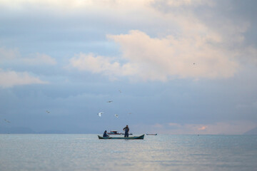 Amanhecer na baía de Paraty, onde um barco de pesca artesanal se destaca na tranquilidade do mar....