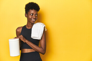 Naklejka premium African woman in sportswear with protein powder and towel
