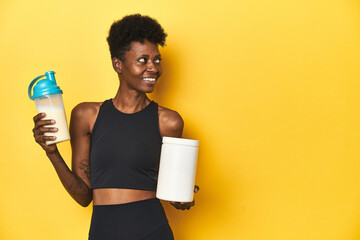 Fototapeta premium African woman in sportswear with protein powder and shake.