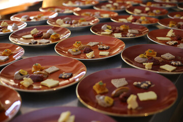 Uma série encantadora de pratos de sobremesas está sendo cuidadosamente montada em um evento corporativo realizado em um restaurante chique. Mini doces típicos brasileiros são dispostos em harmonia,