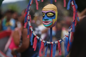 Adereço de mão em forma de peneira enfeitado com uma máscara de papel machê, tradicional de Paraty, e fitas coloridas durante o animado carnaval desta encantadora cidade.