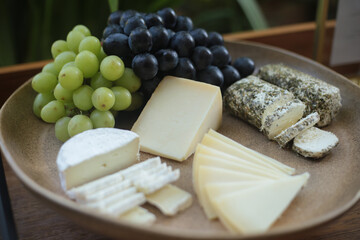 Seleção requintada de queijos finos com uvas em uma mesa de evento social.