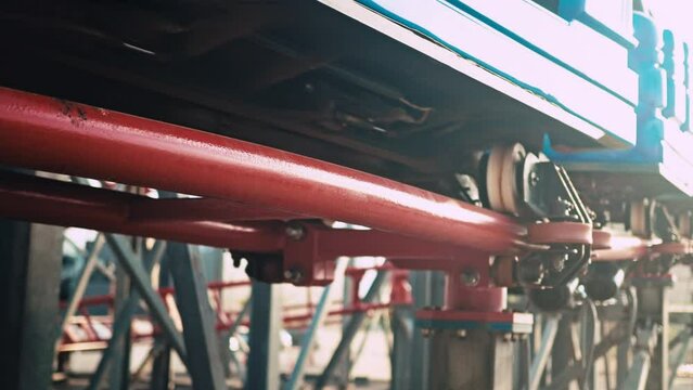 Close up of twisting red roller coaster in slow motion with sun reflections. Funfair and amusement park