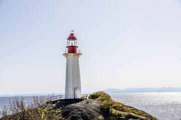 Stone lighthouse with a red top  by the ocean