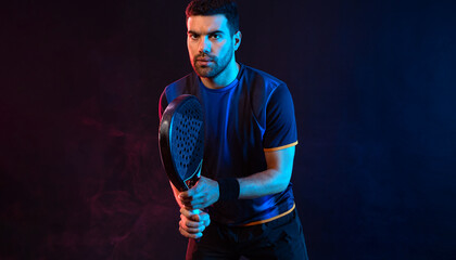Padel tennis player with racket. Man athlete with paddle racket on court with neon colors. Sport...