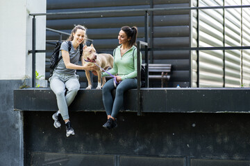 After  jogging, the two girls relax and have fun with their dog, cherishing moments of laughter.