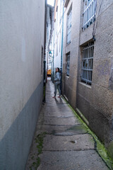 Obraz premium Santiago de Compostela, La Coruna, Galicia, Spain - 12 June, 2023. Tourist walking in a narrow street at city center