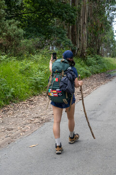 Young woman pilgrim taking a selfie on a trail of the way of saint james. Camino de Santiago. Vertical shot.
