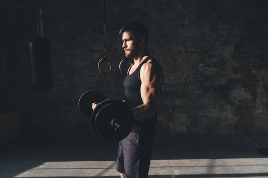 Muscular sportsman with heavy barbell weightlifting