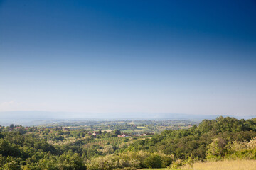 Panorama of a typical European countryside landscape, farms, agricultural fields, trees, in a valley, in Sopot Municipality, Central Serbia, in Kosmaj mountain, in a traditional European rural environ