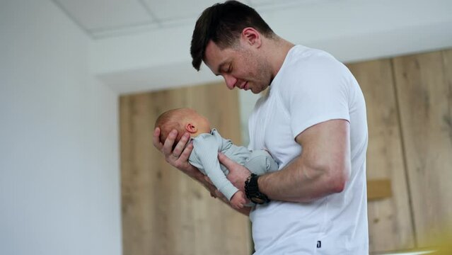 Smiling happy Caucasian father dandling his newborn baby boy. Loving dad with a child low angle view.
