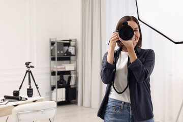 Young professional photographer taking picture in photo studio, space for text