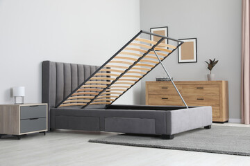 Comfortable bed with storage space for bedding under lifted slatted base in stylish room