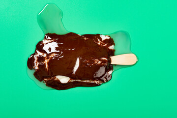 mostly melted chocolate outer with milk and blueberry flavors popsicle on green background