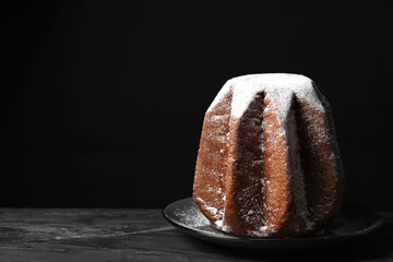 Delicious Pandoro cake decorated with powdered sugar on dark table, space for text. Traditional...