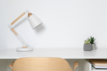 Stylish modern desk lamp and potted succulents on table near white wall indoors