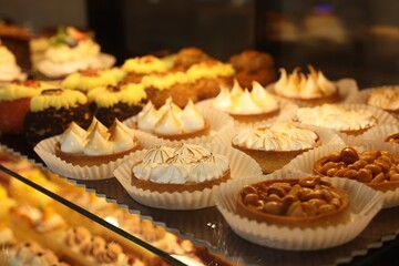 Different tasty tartlets on counter in bakery shop, closeup. Space for text