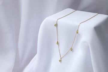 Stylish presentation of necklace on white cloth. Space for text