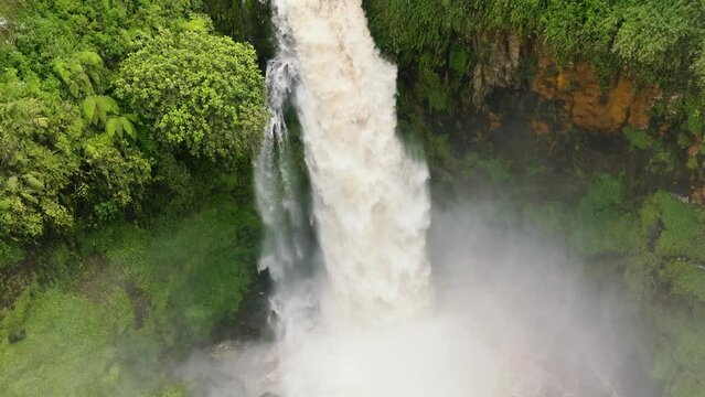 Aerial drone of waterfall in green forest. Telun Berasap Falls in jungle. Sumatra, Jambi, Indonesia.