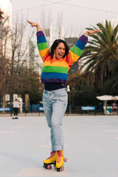 chica latina sonriente con polera de arco&iacute;ris y patines estilo 80s 90s disfrutando del d&iacute;a.