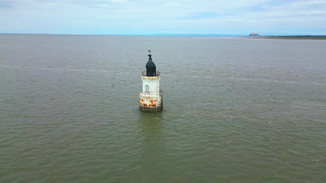 Small lighthouse at high tide with reveal of nuclear power station and coastline at Plover Scar Lighthouse, Lancashire, UK