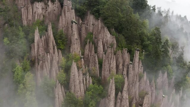 Aerial view rotating away from the Ritten Earth Pillars, in foggy Tyrol, Italy