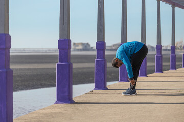 Latino young man stretching in a pergola in a public park.