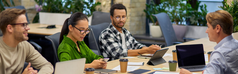 Group of young multiracial business people sitting at desk in the board room and working on project together, discussing work and sharing ideas