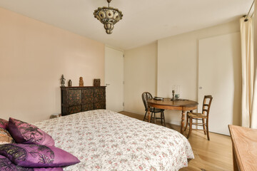 a bedroom with a bed, dresser and table in the fore - image is taken from another room that has...