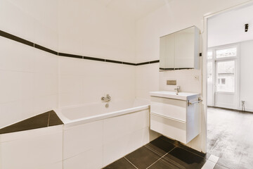 a bathroom with black and white tiles on the walls, sink, mirror and toilet in the room is empty