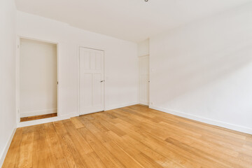 Fototapeta na wymiar an empty room with white walls and wood flooring on one side, there is a door in the other corner