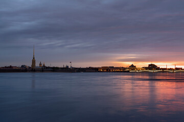 Fototapeta na wymiar View of the Peter and Paul Fortress and the Neva River against a pink dawn sky with clouds on a sunny spring morning, St. Petersburg, Russia
