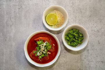 Top view of a bowl of chicken birria with toppings.
