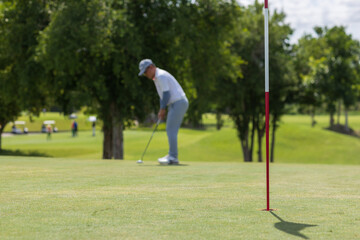 Obraz premium Golfers putting golf balls on the green amid the warm sunshine in the morning. Concept of Outdoor activities and Outdoor sports, Concept of Golfer and Lifestyle.