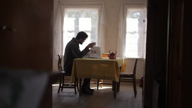 Archive old, man reading newpaper at kitchen table, low angle