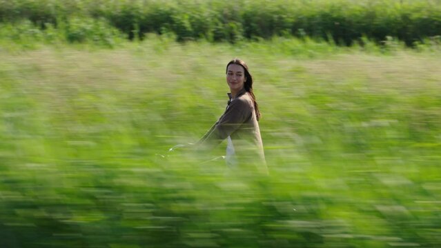 Attractive caucasian woman cycles along lush Dutch river bank, parallel tracking