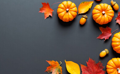Autumn and thanksgiving decoration concept made from autumn leaves and pumpkin on dark background. Flat lay, top view with copy space