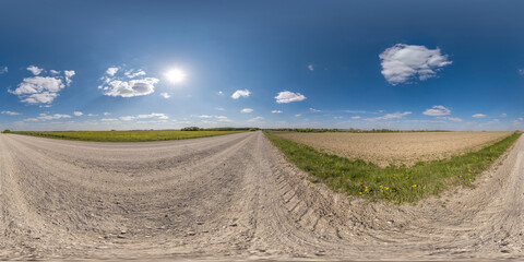 Fototapeta na wymiar 360 hdri panorama on gravel road with clouds and sun on blue sky in equirectangular spherical seamless projection, use as sky replacement in drone panoramas, game development sky dome or VR content