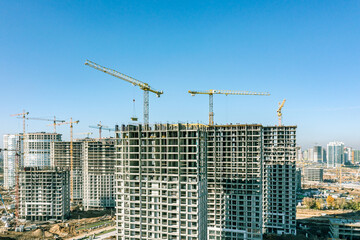 construction site with cranes and apartment buildings under construction against blue sky. housing construction concept. aerial photo.