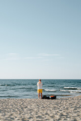 Rear view of an unrecognizable lonely old man on the beach by the sea