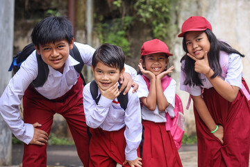 Group of happy elementary school students in uniform looking at camera smiling and showing funny...