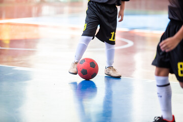 Kid futsal player control the ball for shoot to goal. Indoor soccer sports hall.