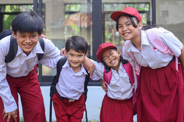 Happy cute school children in uniform standing in row with holding each other and showing smile to camera