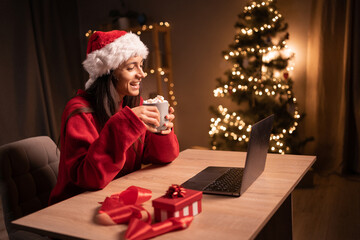 Obraz na płótnie Canvas Young happy woman congratulation with Christmas her family while having video call over a computer at home.