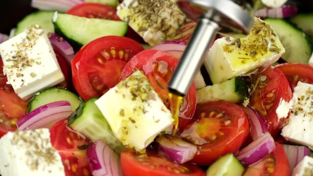 Zoom frame pouring olive oil on greek salad. Fresh vegetable salad, mediterranean cuisine