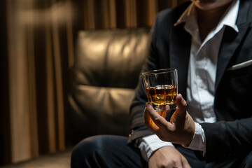 Businessman sitting Holding a Glass of Whiskey Drink Whiskey in the liquor store room