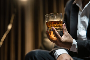 Businessman sitting Holding a Glass of Whiskey Drink Whiskey in the liquor store room