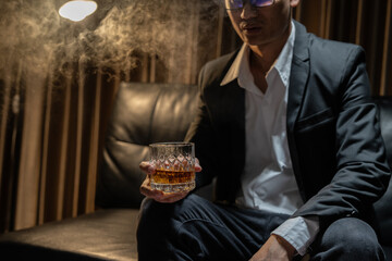 Businessman sitting and holding glass of whiskey