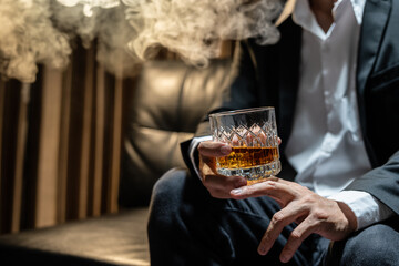Businessman sitting Holding a Glass of Whiskey Drink Whiskey in the liquor store room