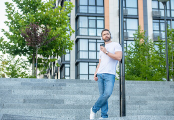 man in music headphones standing outside. man in music headphones with coffee. man in music headphones outdoor. man in music headphones in the street